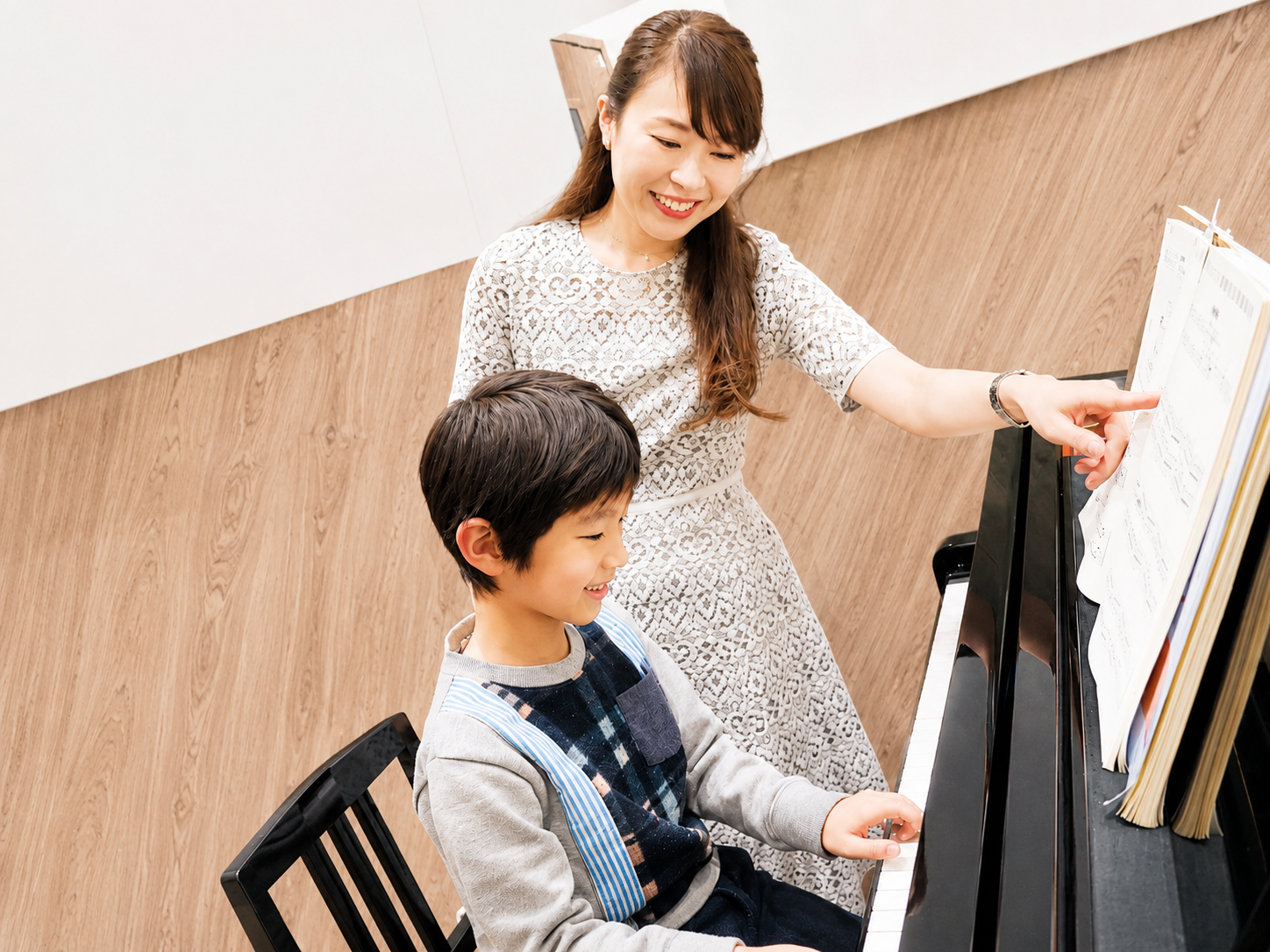 先生が楽譜を指しながら子どもにピアノを教える様子