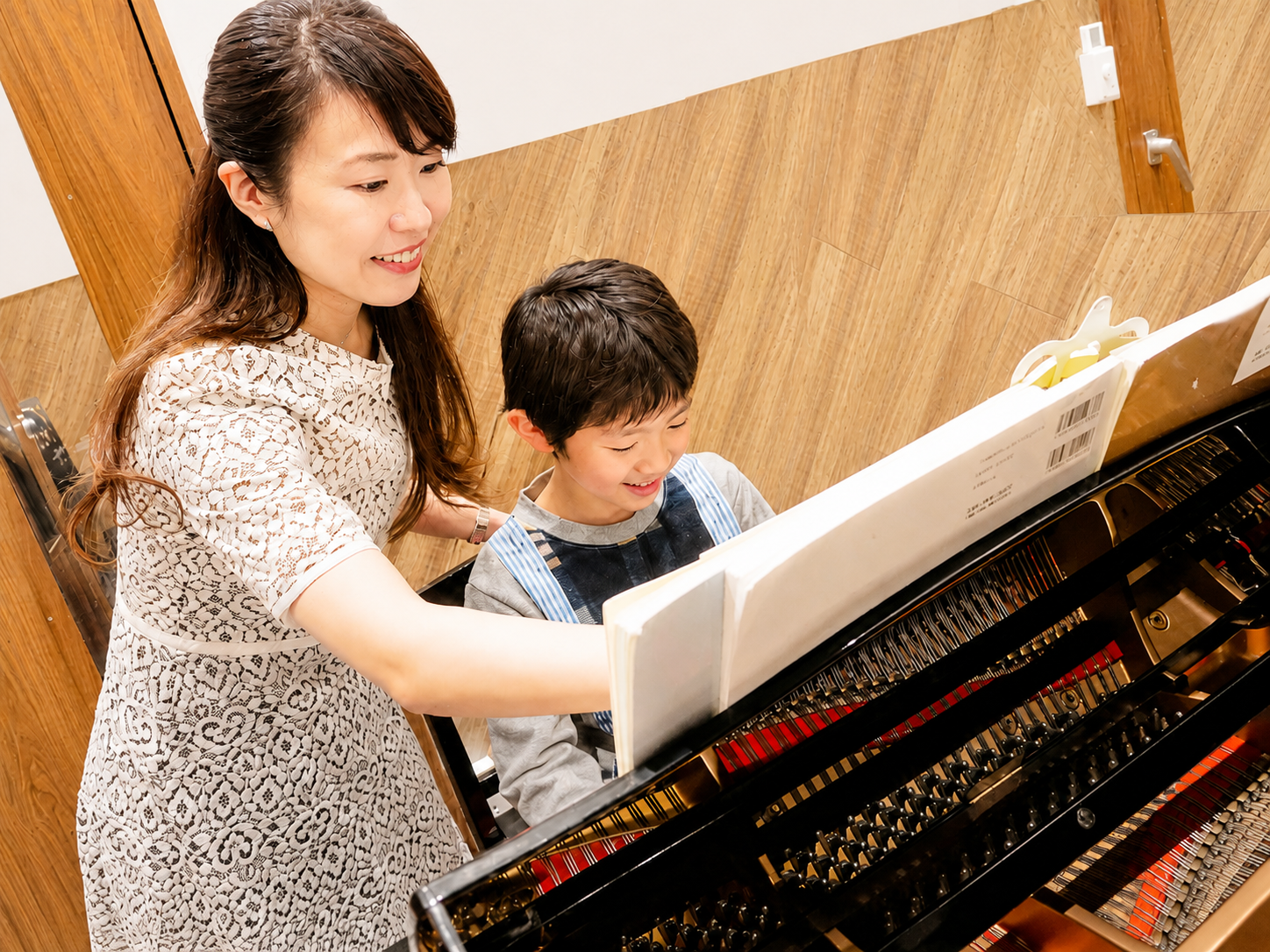 先生が楽譜を見ながら子どもに教えるピアノレッスン