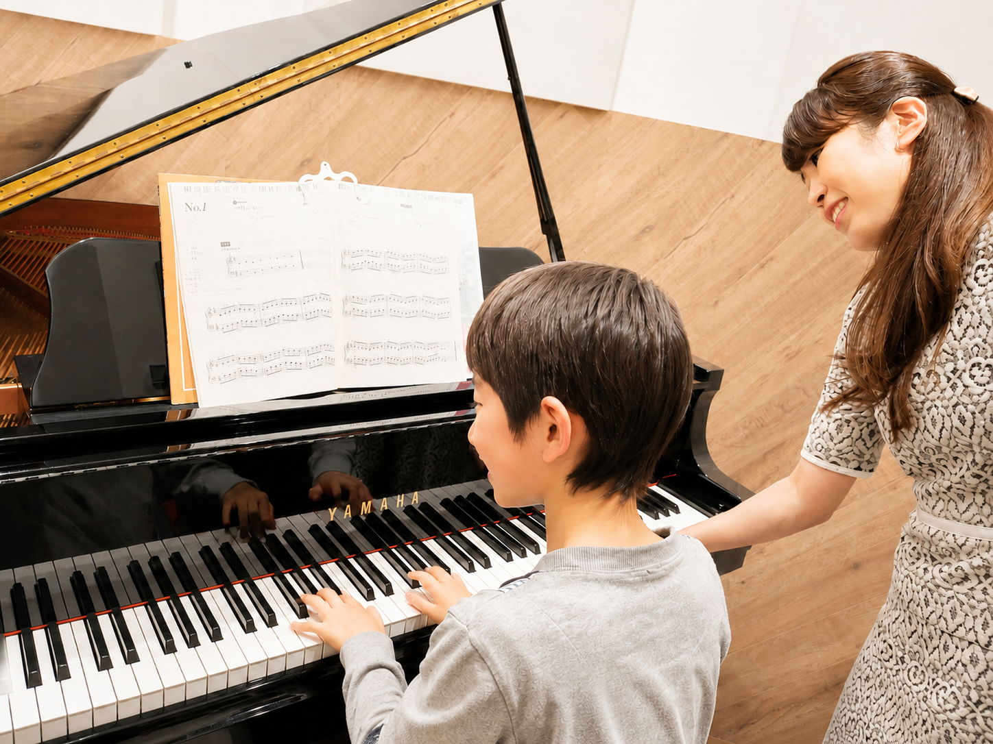 先生が見守る子どものピアノレッスン風景